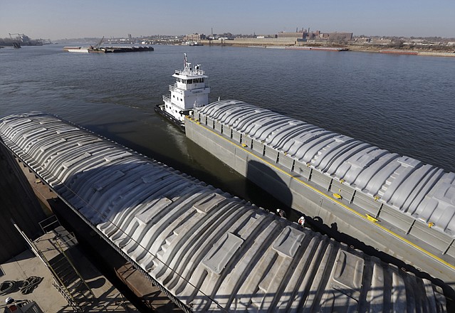 A tow switching barges pulls an empty barge alongside one filled with soybeans at an Archer Daniels Midland grain river terminal along the Mississippi River in Sauget, Ill. Several states are involved in a war over water use on the Missouri and Mississippi rivers.