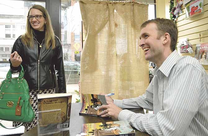Jessica Dulle, at left, shares a laugh with local author Adam Veile and others Thursday as he signs copies of his action-adventure novel, "The Dreamcatcher Adventures: Greedy Jack Wallace" at Downtown Book and Toy in Jefferson City.