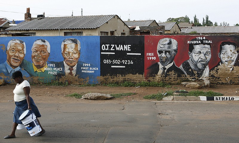 A woman walks past a mural depicting deferent portraits of former South African President Nelson Mandela in Soweto, South Africa. Mandela was admitted to the 1 Military Hospital in Pretoria at the weekend and South Africa's presidency says Mandela is suffering from a recurring lung infection and is responding to treatment.