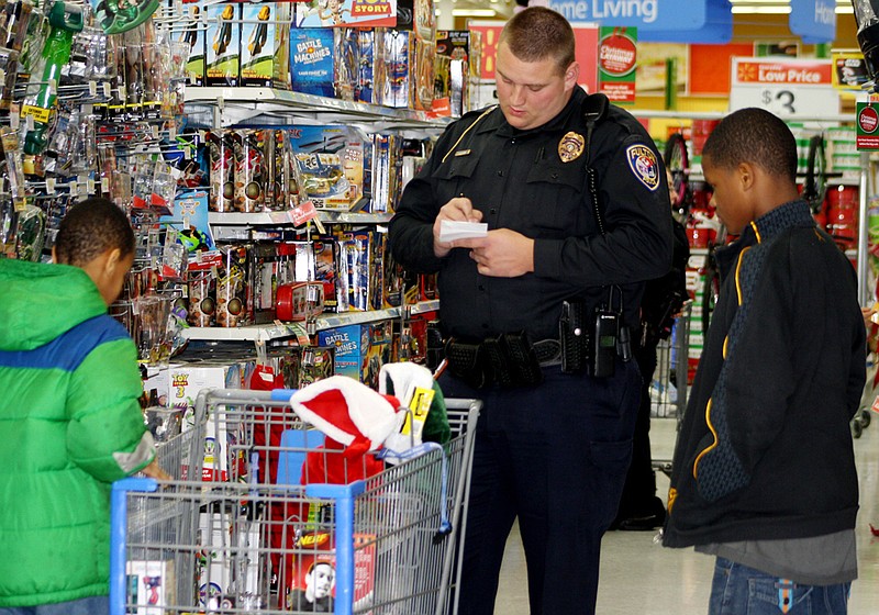 Fulton Police Officer Lance Reams totals purchases by brothers Ammod and Damariya Davis during the annual Shop With A Cop event last year at Walmart in Fulton.