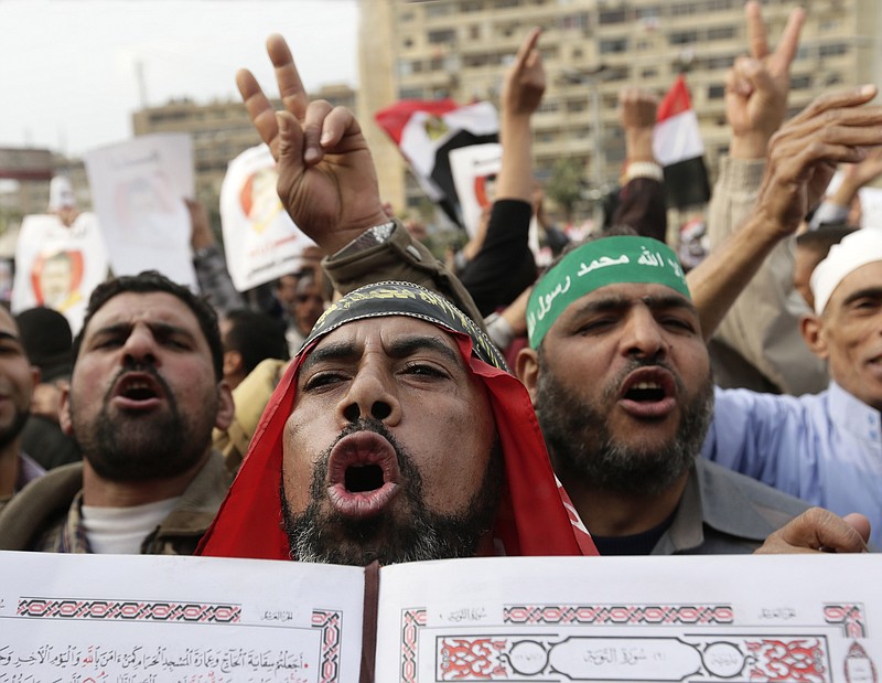 Supporters of Egyptian President Mohammed Morsi chant slogans as one holds up the Quran, Islam's holy book, during a demonstration after Friday prayers in Cairo, Egypt. Opposing sides in Egypt's political crisis were staging rival rallies on Friday, the final day before voting starts on a contentious draft constitution that has plunged the country into turmoil and deeply divided the nation.