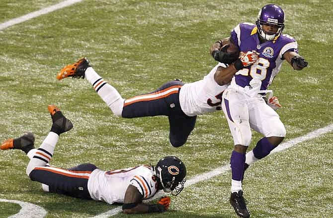 Minnesota Vikings running back Adrian Peterson, right, tries to break a tackle by Chicago Bears linebacker Nick Roach, center, and cornerback Charles Tillman, left, during the second half of an NFL football game Sunday, Dec. 9, 2012, in Minneapolis.