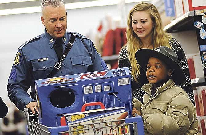 Jordan White, right, checks to make sure he has everything he came for as Missouri Highway Patrol Sgt. Bruce Reinkemeyer and his daughter, Sara Beth, escort Jordan on his shopping adventure during the annual Operation TOYS (Take Our Youth Shopping) at Walmart East in Jefferson City on Saturday morning.