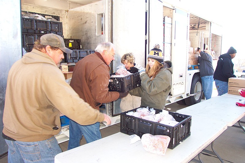 Before the nearly 100 families can receive their monthly portion from the Central Missouri Food Bank's Mobile Food Pantry, dozens of community volunteers like Eugene Moll, Donald Smith, Ramona Hentges and Terry Gawrilur, unload the truck and organize an assembly line delivery process.