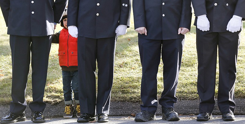 A child peers through firefighters standing Wednesday as the procession heads to the cemetery outside the funeral for school shooting victim Daniel Gerard Barden at St. Rose of Lima Catholic Church in Newtown, Conn., Wednesday.