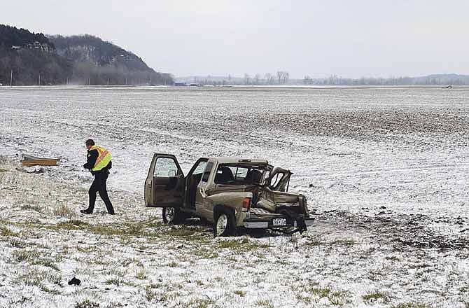 A Jefferson City Police officer walks away from the wreckage of a Ford Ranger pickup truck while investigating a two-vehicle accident on Missouri 94 near the intersection with Cooper Drive on Thursday afternoon. The pickup skidded on the slick road and spun into the path of another truck. Five people were injured. 