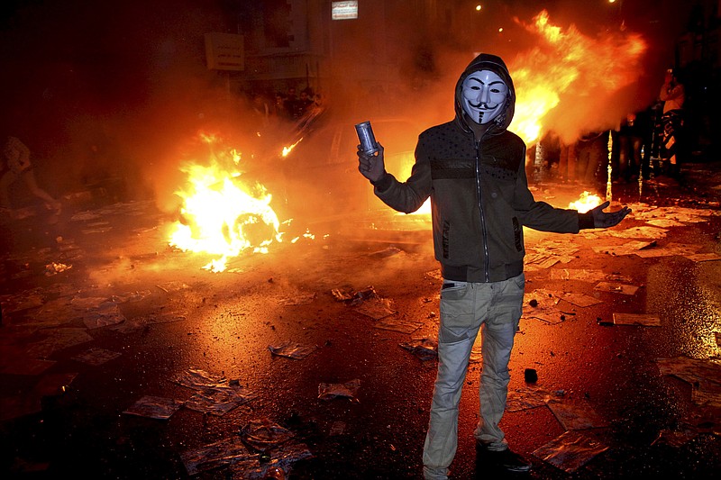 A masked protester poses Friday with a tear gas canister in front of a burning vehicle during clashes between opponents of Egyptian President Mohammed Morsi and his Islamist supporters in Alexandria, Egypt. 