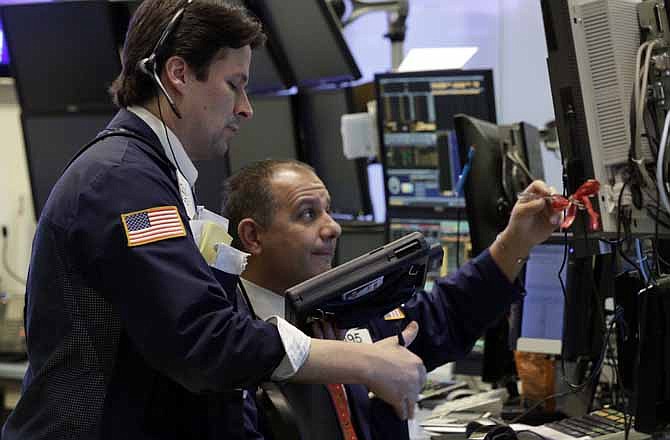 In this Friday, Dec. 14, 2012, photo, Traders Patrick McKeon, left, and Joel Lucchese work on the floor of the New York Stock Exchange.