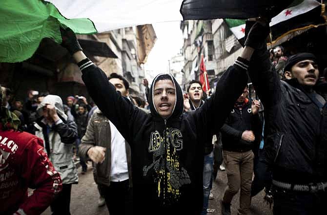 Syrians carry a large revolution flag and chant slogans during a protest in Aleppo, Syria, where young people and children sang songs against Bashar Assad and the Syrian regime, Friday, Dec. 21, 2012. (AP Photo/Virginie Nguyen Hoang)