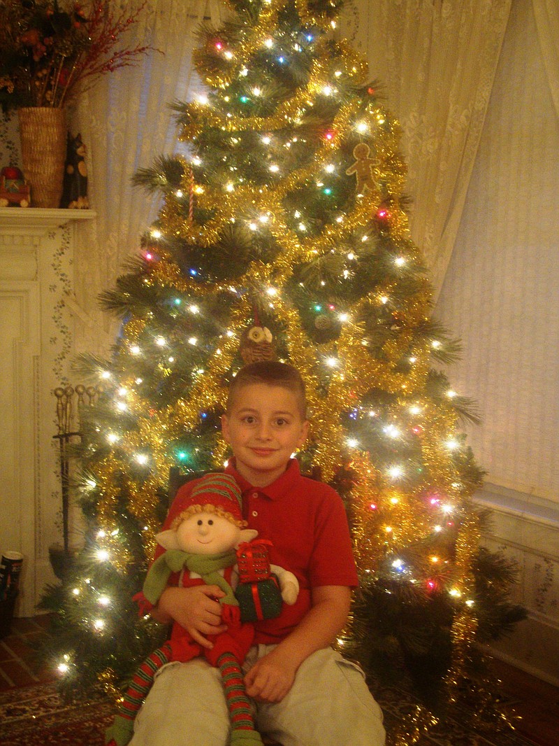 Calvin Guerrero sits with his new elfin pal, William, in front of his family Christmas tree in Yorkville, Ill.