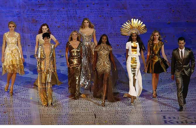 This Sunday Aug. 12, 2012 file photo shows models, from left, Lily Cole, Karen Elson, Stella Tennant, Kate Moss, Lily Donaldson, Naomi Campbell, Jourdan Dunn and Georgia May Jagger walking with a male model during the Closing Ceremony at the 2012 Summer Olympics in London. Gold was the new black at the closing ceremony with a parade of supermodels wearing gilded gowns in a tribute to British fashion. Kate Moss and Naomi Campbell both had on Alexander McQueen, Georgia May Jagger's was by Victoria Beckham, Karen Elson was in Burberry, and Stella Tennant donned a Christopher Kane Swarovski-crystal catsuit.