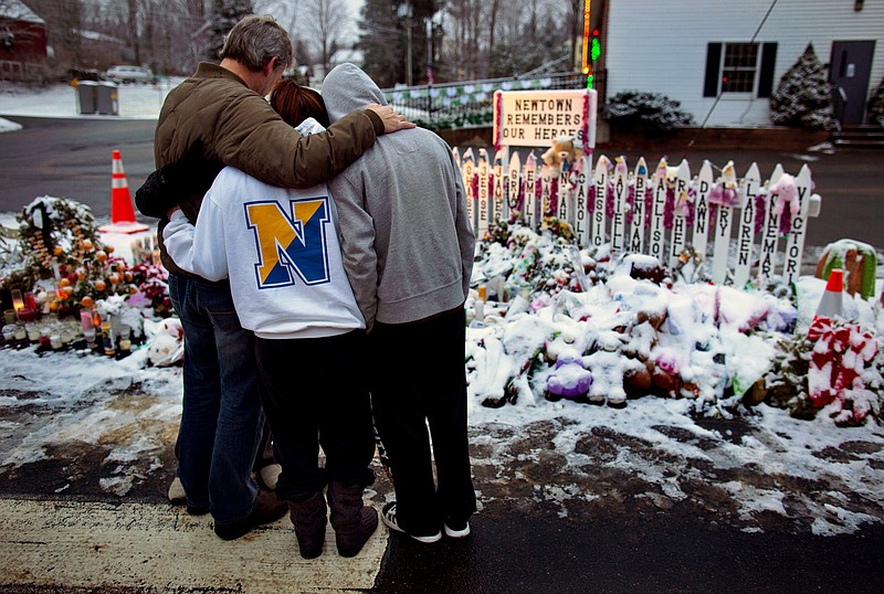 Members of the Rutter family of Sandy Hook, Conn., embrace early Christmas morning as they stand near memorials by the Sandy Hook firehouse in Newtown, Conn. People continue to visit memorials after gunman Adam Lanza walked into Sandy Hook Elementary School in Newtown, Conn., Dec. 14, and opened fire, killing 26, including 20 children, before killing himself.