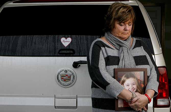 In this Saturday, Dec. 22, 2012 photo, Judy Neiman holds a photo of her daugher, Sydnee, in front of her 2006 Cadillac Escalade at her home in West Richland, Wash. Sydnee died in late 2011 after Neiman accidentally backed over her with the SUV. Although there is a law in place that calls for new manufacturing requirements to improve the visibility behind passenger vehicles, the standards have yet to be mandated because of delays by the U.S. Department of Transportation.