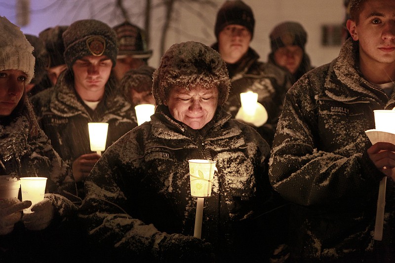 West Webster firefighter Vicki Polkowski, center, sheds tears Wednesday in Webster, N.Y., as the Fireman's Prayer is read aloud at a candlelight vigil held in honor of the firefighters that were injured and killed on Christmas Eve.