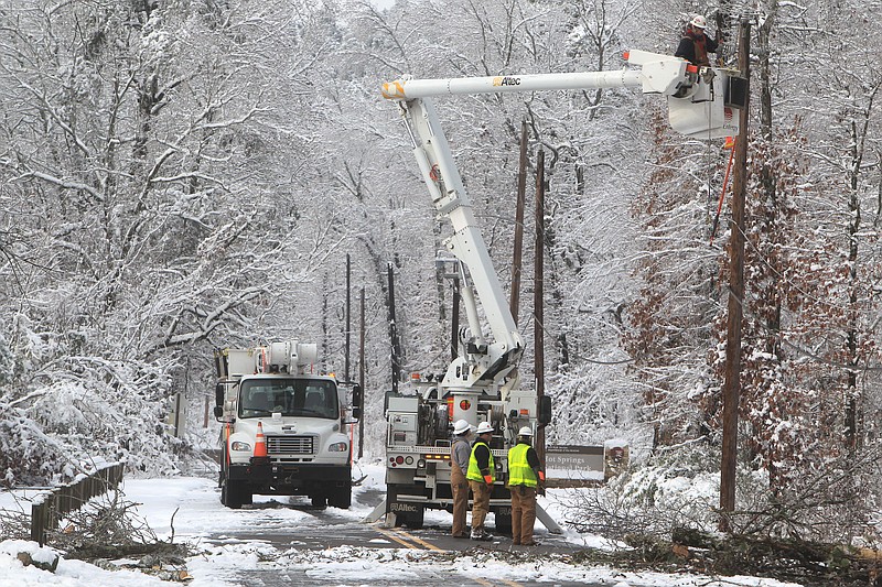 An Entergy Arkansas Inc. crew works Thursday to restore power to customers on Whittington Avenue near the entrance to Hot Springs National Park in Hot Springs, Ark. A Christmas Day storm dumped between 6 to 15 inches of snow, knocking out power to about half of the 61,000 customers in Garland County.