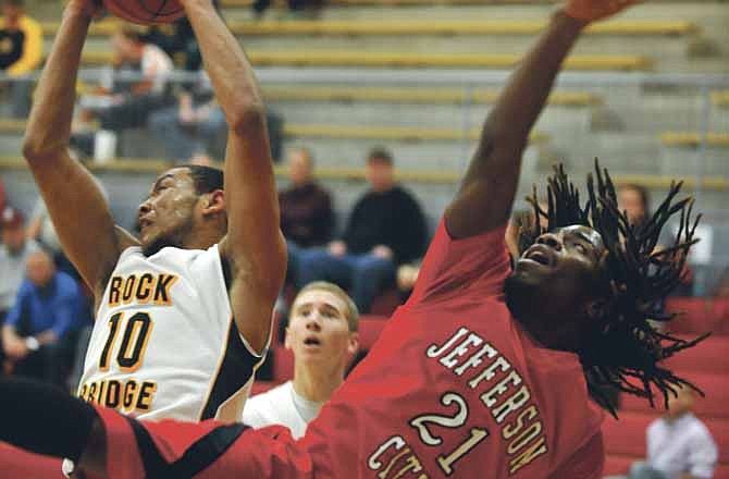 Aaron Session of Jefferson City and Vencel Tigue of Rock Bridge fall backward while going for a rebound during Saturday's game at Fleming Fieldhouse.