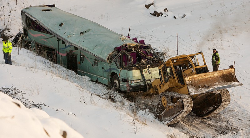 A piece of heavy equipment strains to move a bus which plummeted 200 feet down an embankment in rural Eastern Oregon Sunday, killing nine and sending multiple to hospitals, Monday. Survivors of the bus crash said Monday some passengers were thrown from the tour bus through broken windows after the vehicle skidded out of control, smashed through a guardrail and went 200 feet down an embankment. 