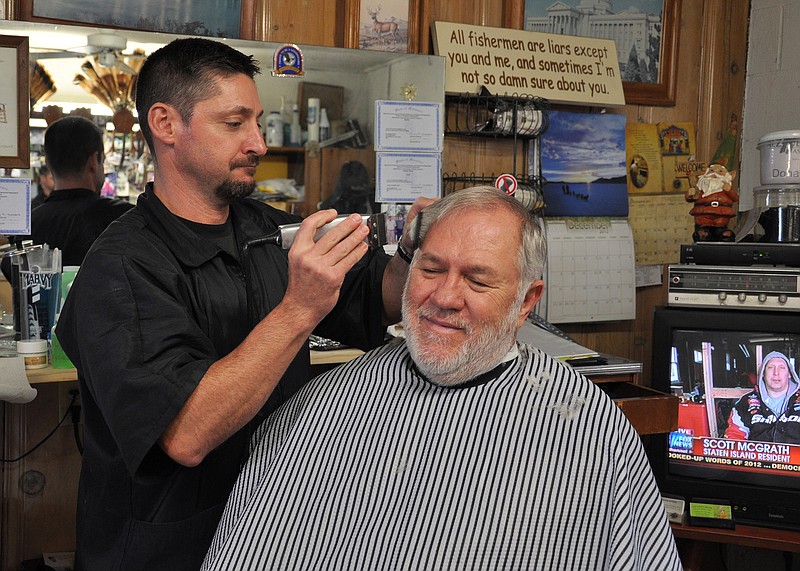 Missouri National Guard retired Master Sgt. Mike Tanner, left, cuts Rich McCarty's hair at his barber shop in Jefferson City. Tanner used his Post-9/11 GI Bill benefits to attend the Missouri School of Barbering and Hairstyling after he retired from the Guard in the spring.