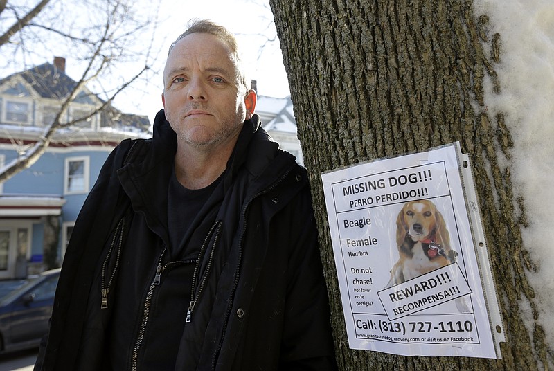 Author Dennis Lehane stands next to a poster for his missing dog in Brookline, Mass., on Thursday. The dog, a beagle named Tessa, went missing on Christmas Eve. The author has promised a special reward for finding the dogÂ­ - a spot in his next book.  