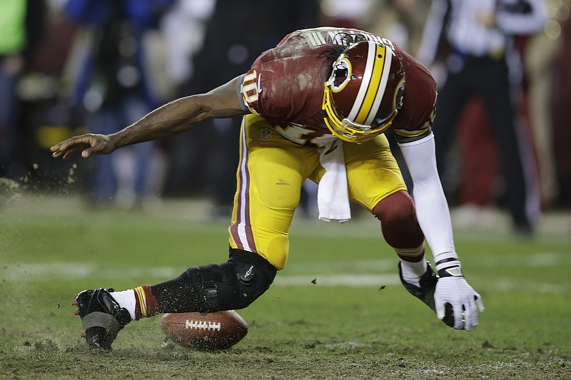 Washington Redskins quarterback Robert Griffin III twists his knees as he reaches for a loose ball after a low snap during the second half of an NFL wild card playoff football game against the Seattle Seahawks in Landover, Md., Sunday, Jan. 6, 2013. 
