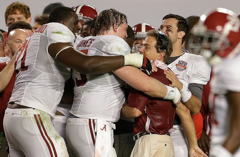 Alabama head coach Nick Saban is hugged by (from left) Cyrus Kouandijo, Barrett Jones and A.J. McCarron in the final minute of Monday's win against Notre Dame in Miami.