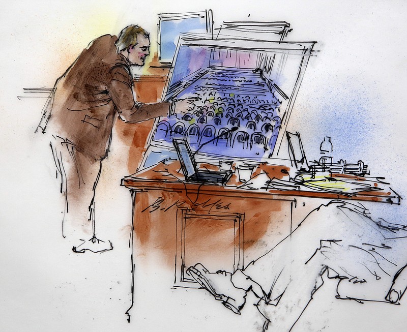 This courtroom sketch shows Aurora Police Detective Matthew Ingui pointing to a large photograph of the inside of the Century 16 theater as he testifies at a preliminary hearing for suspected Aurora theater shooter James Holmes at preliminary hearing in district court in Centennial, Colo., on Monday.