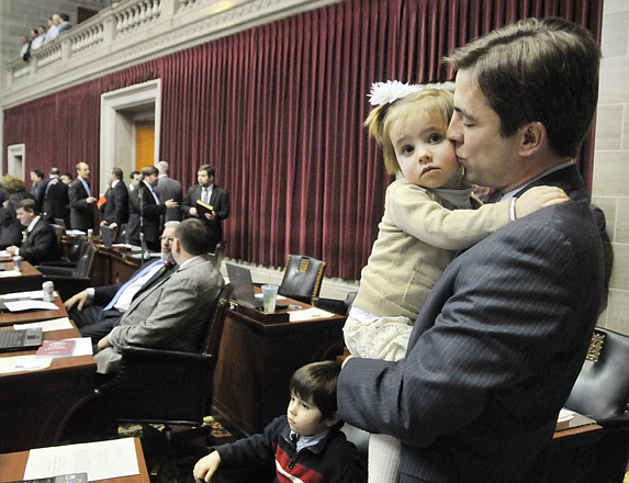 Jay Barnes, R-Jefferson City, holds his 2-year-old daughter, Maggie, and tries to soothe her nerves in the crowd as she and her 4-year-old brother, Atticus, seated, joined their dad on the Floor of the House for swearing-in ceremonies to kick off the 2013 legislative session. This marks Barnes' second term in the House.