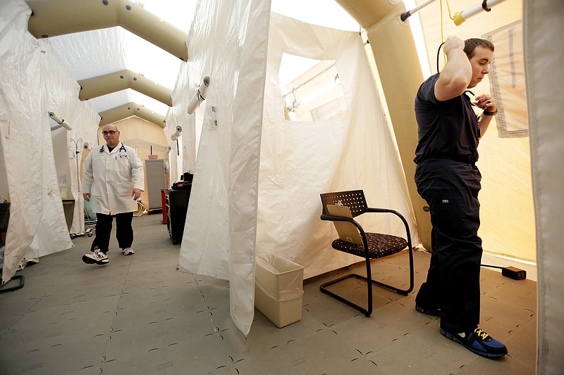 Physician assistants Scott Fillman, left, and Andrew Hunadi meet with patients, not pictured, in a tent set up for people with flu symptoms, just outside the emergency entrance at the Lehigh Valley Hospital Thursday in Allentown, Pa.