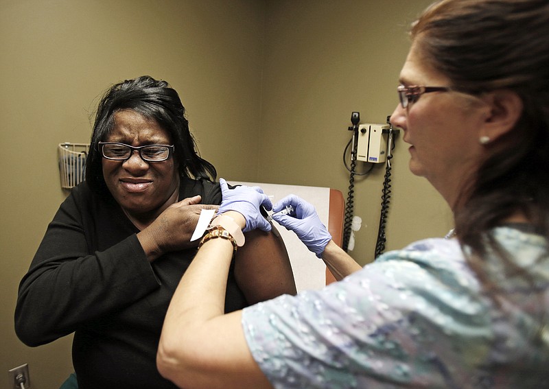 Nurse Debbie Smerk, right, administers a flu shot to Pamela Black on Thursday at MetroHealth in Cleveland. Ohio health authorities reported Friday that a child has died from flu complications, as the state's flu-associated hospitalizations continue to climb at much higher rates than the last two flu seasons.