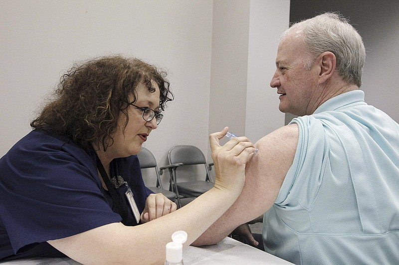 In this file photo taken Oct. 17, 2012, Bill Staples, a Mississippi Department of Health employee, is given a flu vaccine shot by registered nurse Rosemary Jones, also with the health department, in Jackson, Miss. A survey by Centers for Disease Control and Prevention researchers found that in 2011, more than 400 U.S. hospitals required flu vaccinations for their employees and 29 hospitals fired employees that were not vaccinated against the virus. 