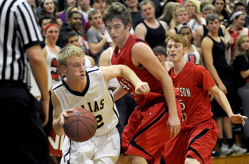 Garrett Buschjost of Helias drives the ball toward the basket as Jays teammates Scott Stegeman (middle) and Dylan Mason defend Tuesday night at Rackers Fieldhouse.