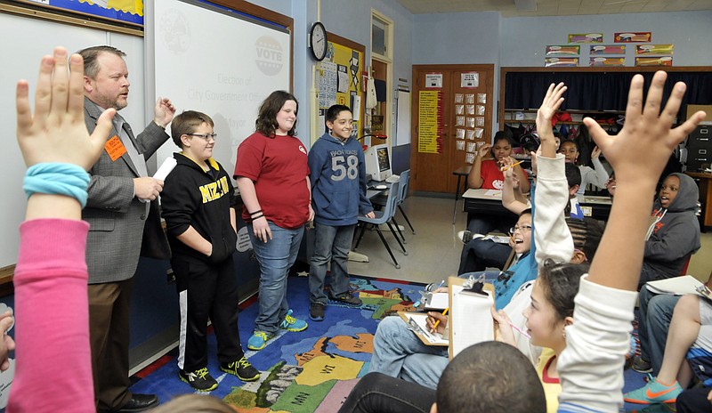 In an effort to create excitement about an essay contest, Jefferson City Mayor Eric Struemph, foreground left, and Second Ward Councilman Shawn Schulte (not pictured), visited with fifth-grade students at South Elementary School. To explain how a primary works, Struemph had three students come to the front of the class and asked their classmates to vote their favorite by which shirt they preferred. The students will use the information they learned to better write their own essays about being Mayor. 