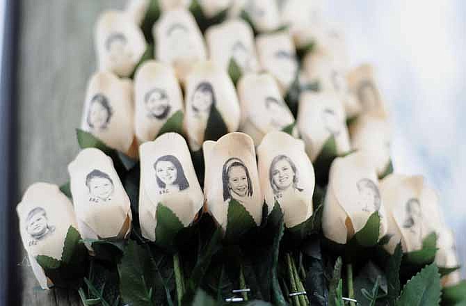 White roses with the faces of victims of the Sandy Hook Elementary School shooting are displayed on a telephone pole near the school on the one-month anniversary of the mass shooting that left 26 dead, including 20 children in Newtown, Conn., Monday, Jan. 14, 2013.