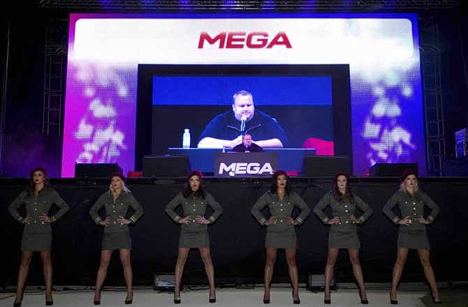 Indicted Megaupload founder Kim Dotcom appears on a large screen during the launch of a new file-sharing website called "Mega" at his Coatesville mansion in Auckland, New Zealand, Sunday, Jan. 20, 2013. The colorful entrepreneur unveiled the site ahead of a lavish gala and press conference on the anniversary of his arrest on racketeering charges related to his now-shuttered Megaupload file-sharing site. 