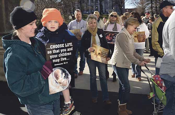 Shelly Ortbals, left, and her 2-year-old son, David, of Russellville make their way into the Capitol building Saturday among others taking part on the Pro-Life March held in Jefferson City. 