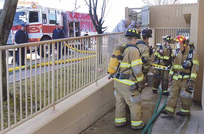 Firefighters assemble around a side entrance to the Holiday Inn Express in Jefferson City on Saturday during their response to a structure fire inside the hotel. 
