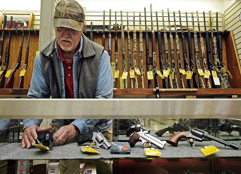 Steve Sandy, a gun salesman at House of Bargains in Apache Flats, arranges some of the few remaining handguns in the store's display case on Monday.