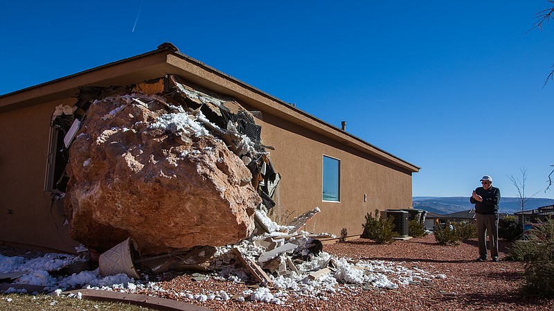 A bystander photographs a 12-by-9-foot boulder as it rests in the master bedroom of a home in St. George, Utah. Wanda Denhalter, 63, was sleeping alone when she narrowly missed being crushed under the boulder early Saturday morning, said her husband, Scot Denhalter.