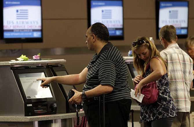 In this Sept. 6, 2012, file photo, passengers use the self service check-in at the U.S. Airways gate at Dallas-Fort Worth International Airport, in Grapevine, Texas. According to a three-month AP investigation released in January 2013, five years after the start of the Great Recession, instead of relying on someone else in the workplace or their personal lives, people are using technology to do tasks independently. 