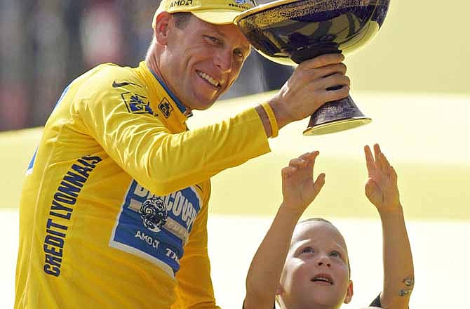 In this July 24, 2005 file photo, Luke Armstrong, rear right, tries to touch the winner's trophy held by his father, Lance Armstrong, after Armstrong won his seventh straight Tour de France cycling race, in Paris. 