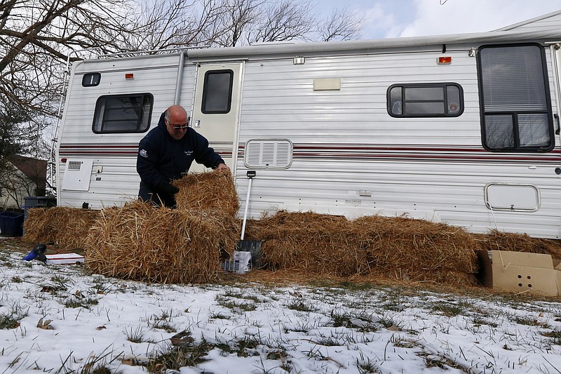 Anthony Cavallo uses hay to insulate his trailer in preparation for a cold night, Wednesday, in Union Beach, N.J. Cavallo had to buy the trailer out of pocket and place it next to his home damaged by Superstorm Sandy because he is yet to receive storm aid. 