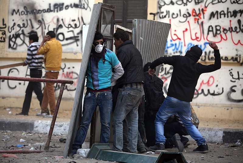 Egyptian protesters take cover Friday as they clash with riot police near Tahrir Square, Cairo, Egypt. Two years after Egypt's revolution began, the country's schism was on display Friday as the mainly liberal and secular opposition held rallies saying the goals of the pro-democracy uprising have not been met and denouncing Islamist President Mohammed Morsi. With the anniversary, Egypt is definitively in the new phase of its upheaval.