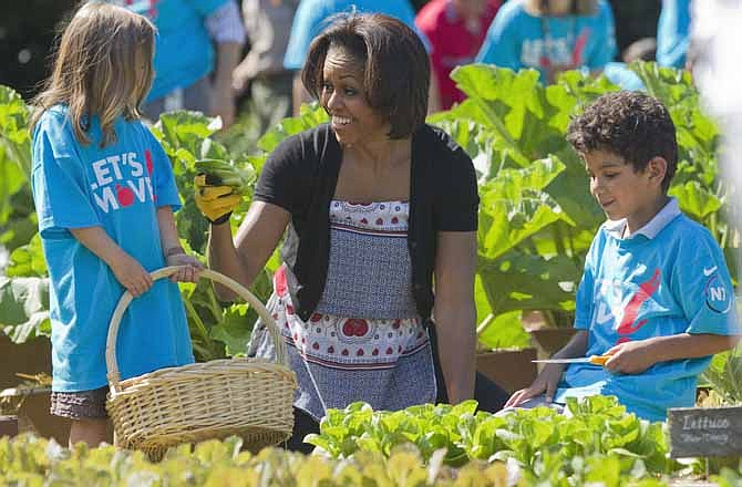 In this June 3, 2011, file photo, first lady Michelle Obama tends the White House garden in Washington, with a group of children as part of the "Let's Move!" campaign. Michelle Obama has a new look, both in person and online, and with the president's re-election, she has four more years as first lady, too. 