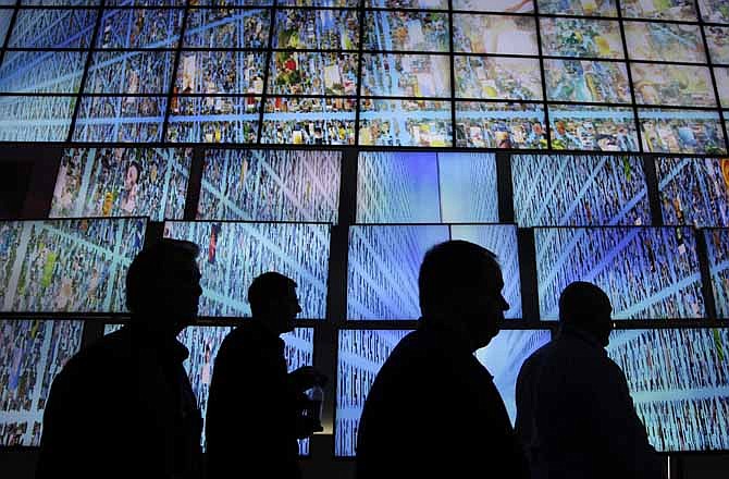  In this Thursday, Jan. 6, 2011, file photo, exhibitors and buyers at the Consumer Electronics Show walk by a display of LG HDTV screens, in Las Vegas.