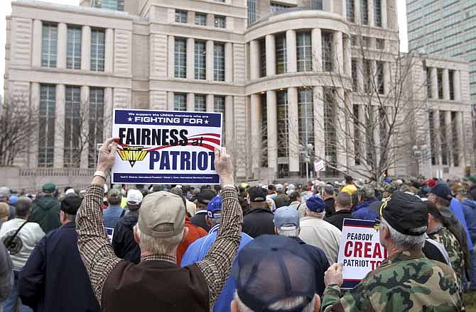 Retired Peabody miner Steven Crooks, left, 63, of Winslow, Ind. holds a sign up during a protest by the United Mine Workers of America, in front of the federal courthouse in St. Louis before marching to Peabody Energy headquarters on Tuesday, Jan. 29, 2013. Ten union mine workers have been arrested following a protest outside Peabody Energy headquarters. Workers and retirees were seeking to draw attention to what they consider poor treatment from Patriot Coal Corp., a company spun off from Peabody five years ago. A hearing on Patriot's bankruptcy was Tuesday in St. Louis. Mine workers said the protest was a bid to save health care and pension benefits that could be stripped away in Chapter 11 proceedings. (AP Photo/St. Louis Post-Dispatch, Stephanie S. Cordle)