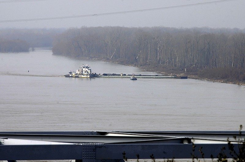 The towboat Natures Way Endeavor banks a barge against the western bank of the Mississippi River, Monday as an 18-wheeler crosses the Interstate 20 bridge. Cleanup crews with booms skimmed oily water from the Mississippi River after a barge leaked nearly 7,000 gallons of oil after striking a railroad bridge near Vicksburg.