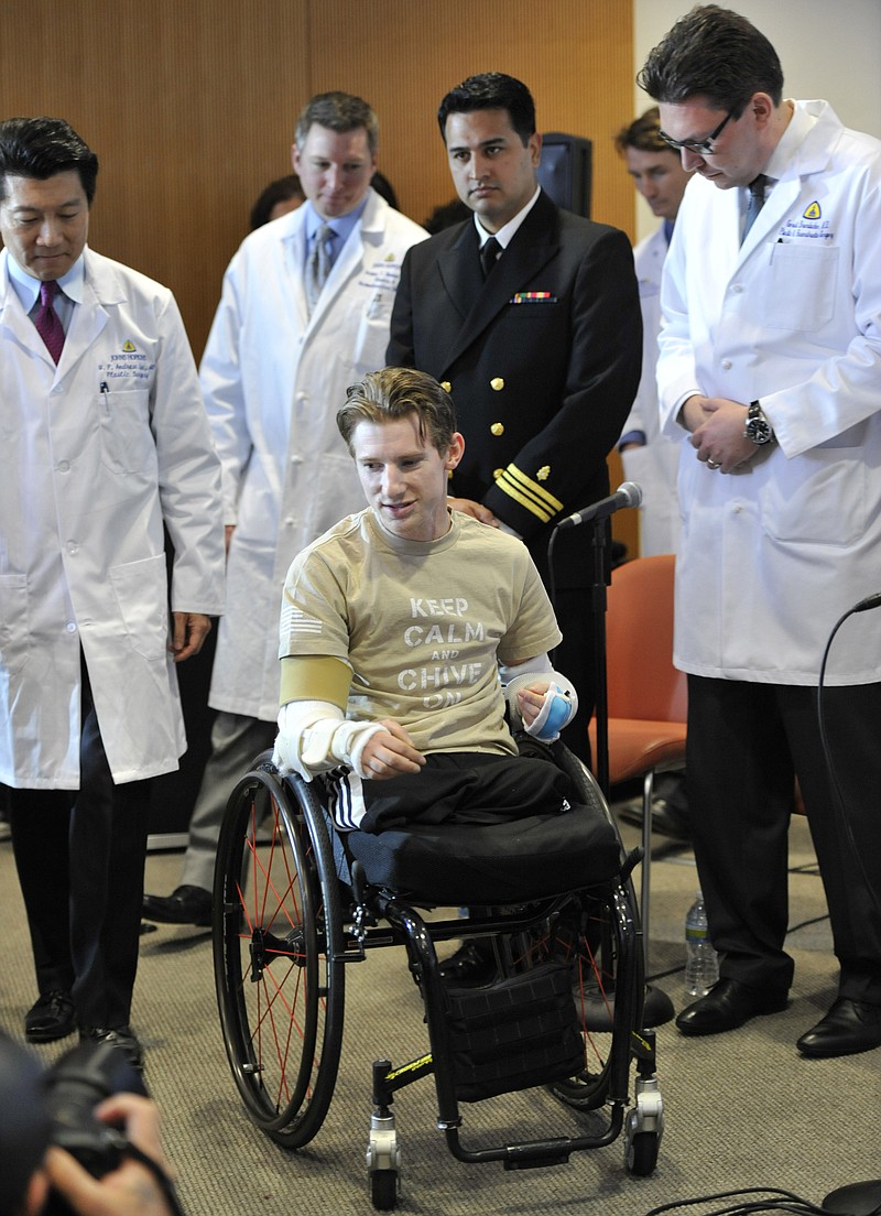 Retired Infantryman Brendan M. Marrocco wheels himself into a news conference followed by surgeons, from left, W.P. Andrew Lee, M.D., Jamie Shores M.D., Patrick L. Basile M.D. and Gerald Brandacher M.D. at Johns Hopkins hospital in Baltimore.  Marrocco received a transplant of two arms from a deceased donor after losing all four limbs in a 2009 roadside bomb attack in Iraq.