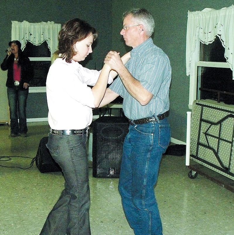 Bruce Rosenmiller, California, teaches his daughter how to two-step at the Moniteau Saddle Club anniversary celebration Saturday.