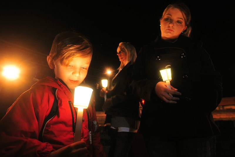 Cade Smith, 6, watches the flame of his candle burn as his mother, Brandi, looks on during a candlelight vigil for the families involved in the ongoing hostage crisis Friday night, Feb. 1, 2013 in Midland City, Ala. The Smith family feels a connection to the autistic boy named Ethan being held hostage because their son, Cade, also has autism.