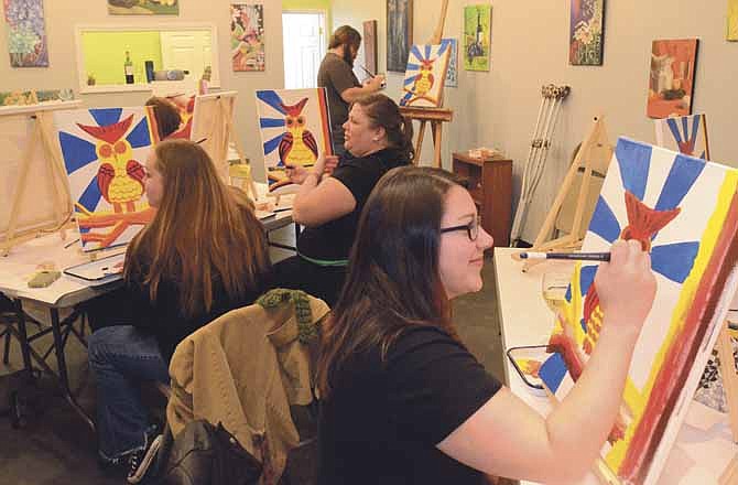 In the Art with a Twist class held at the Mary Kate Johnson Art Gallery, participants paint while enjoying wine or other drinks as they're being instructed by Evan Connor (background). In the foreground is Sarah Johnson, on the left is Beth Shelton and in the center is Jen Maurer.